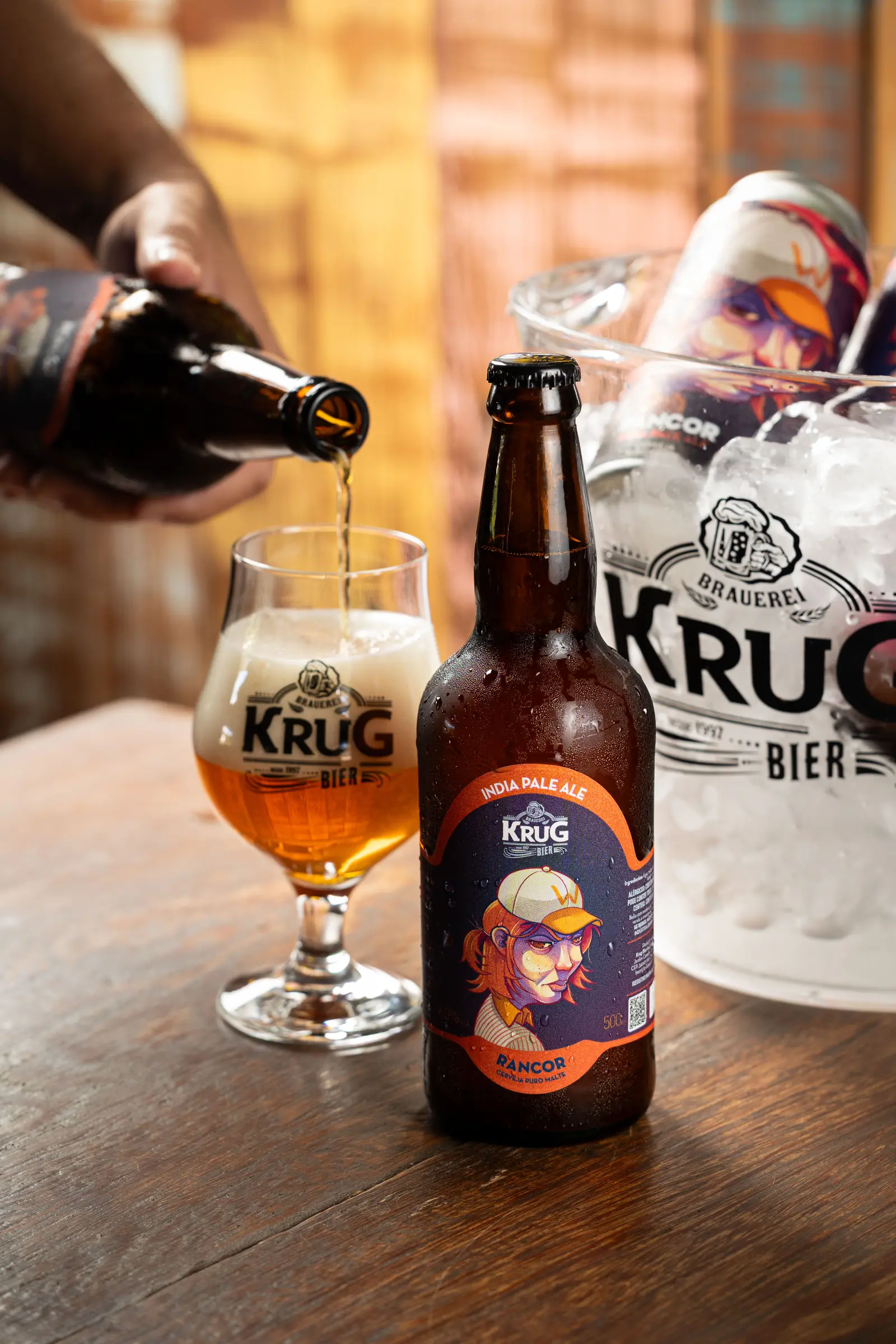 Cerveja Krug Rancor India Pale Ale sendo servida na taça, ao lado do balde de gelo