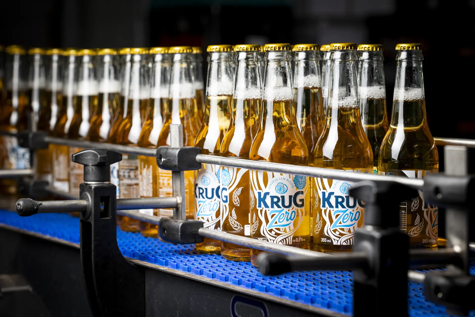 Linha de envase da Krug Bier com garrafas de vidro sendo tampadas